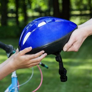 Roll Over Image Bike, Adult handing a child a bike helmet